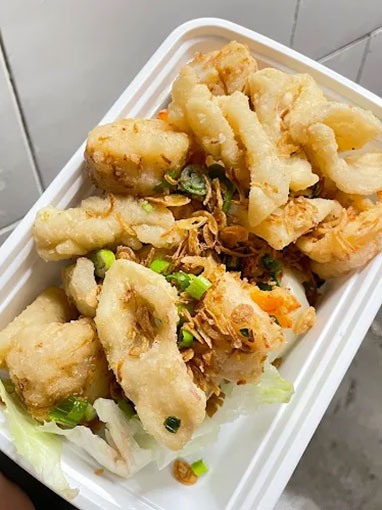 Crispy fried squid pieces with scallions and garlic in a takeout box at Canto House, a Chinese restaurant in Philadelphia