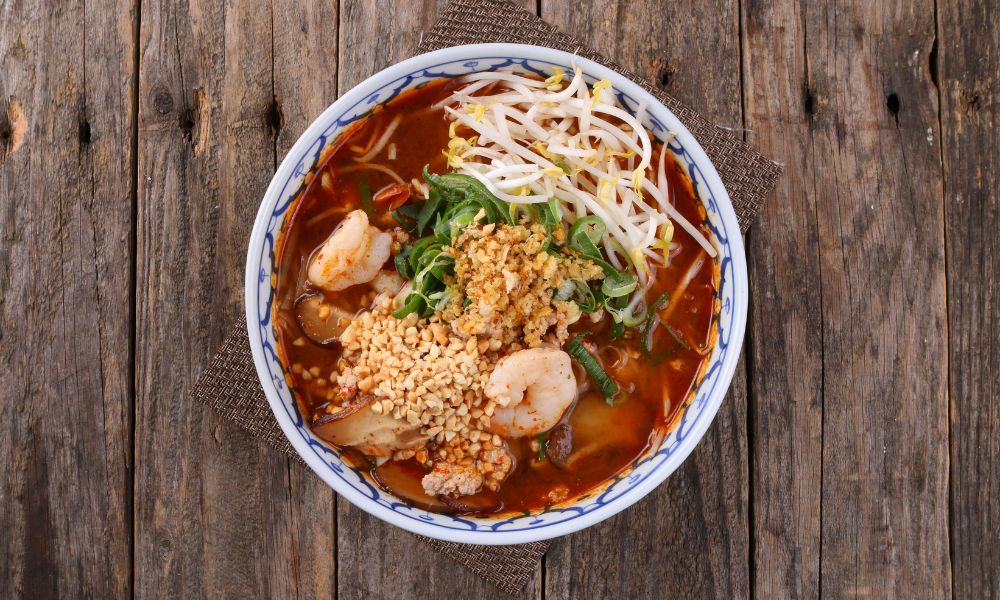 Spicy shrimp noodle soup with bean sprouts, peanuts, and herbs in red broth at Canto House, a Chinese restaurant in Philadelphia