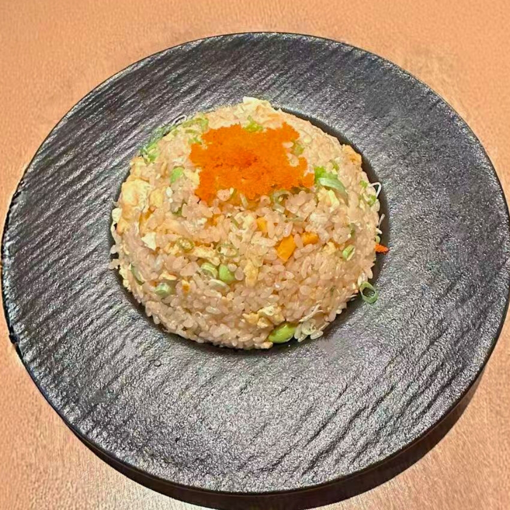Fried rice with crab meat, masago, eggs, and veggies, served on a black plate at Catzuneko Shokudo, a Japanese Restaurant in New York