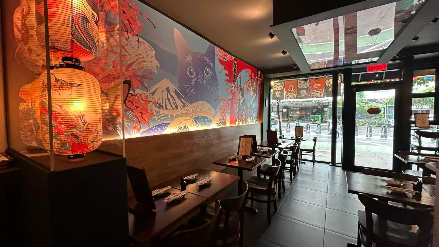 Interior space with Japanese lanterns, cat mural, and neatly arranged tables at Catzuneko Shokudo, a Japanese Restaurant in New York