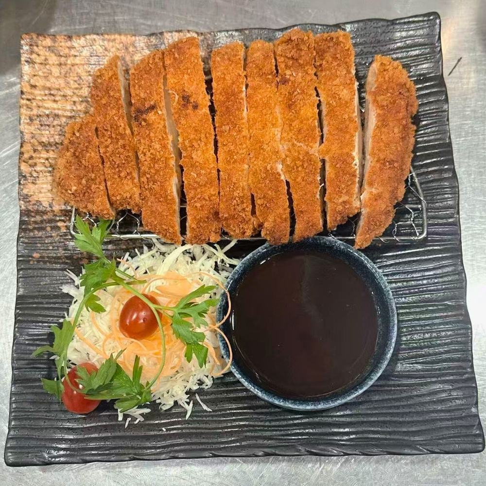 Crispy breaded pork cutlet sliced, served with sauce and shredded veggies at Catzuneko Shokudo, a Japanese Restaurant in New York