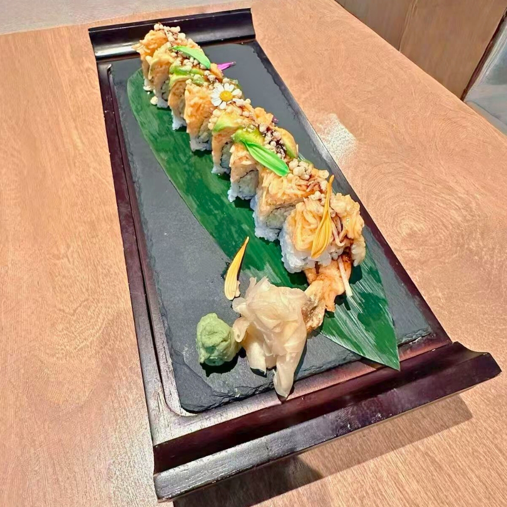 Creative sushi roll garnished with edible flowers, served with wasabi and ginger at Catzuneko Shokudo, a Japanese Restaurant in New York