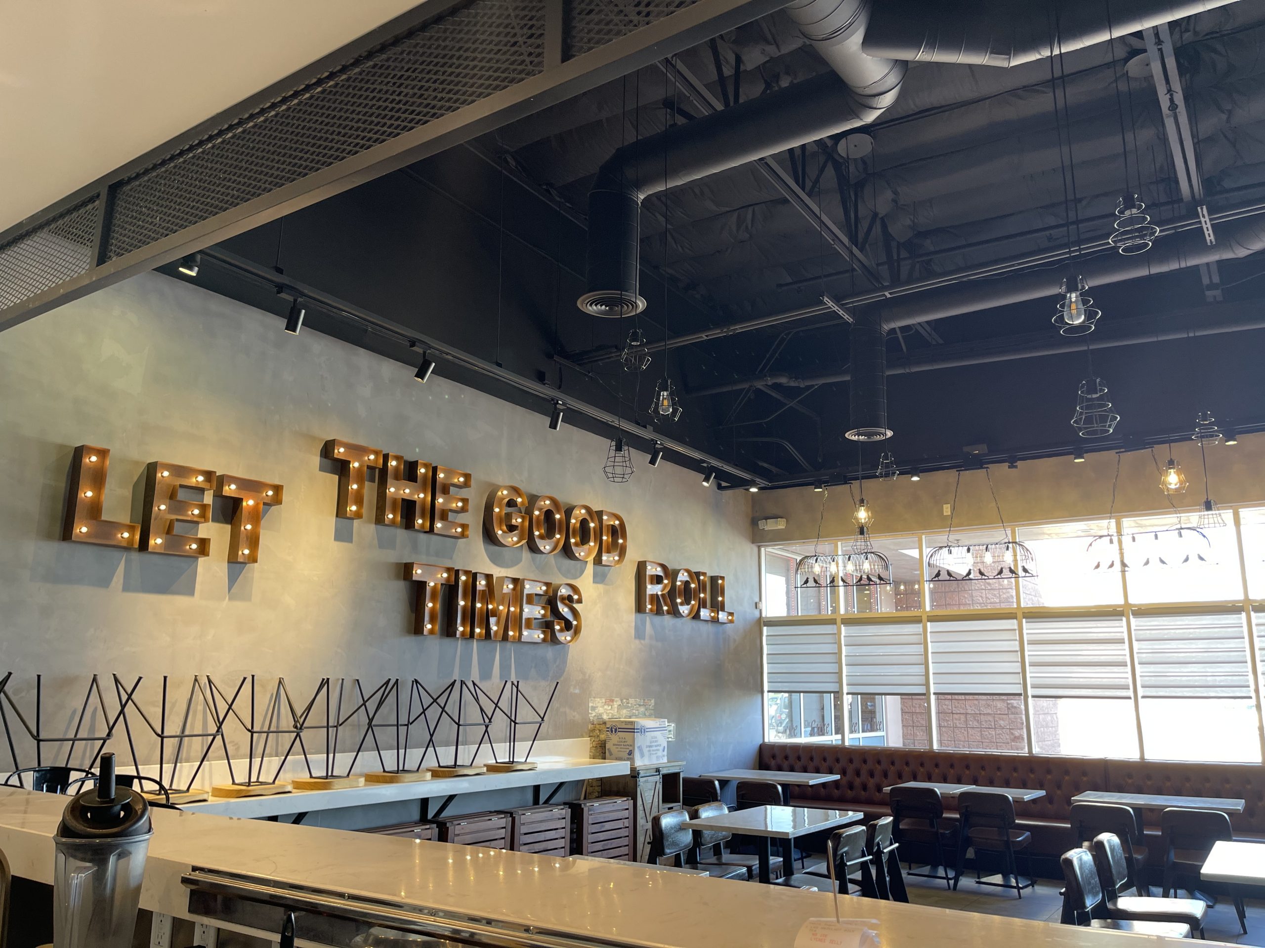 Same restaurant interior from a slightly different angle, emphasizing the lit marquee sign, counter area, and large windows with blinds.