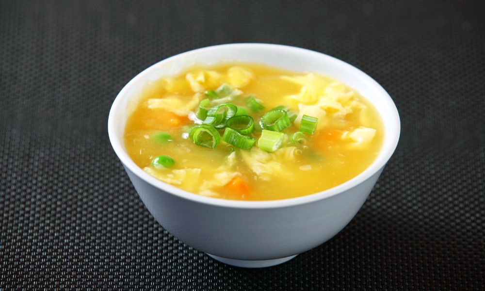Classic egg drop soup with green onions, peas, and carrots in a bowl at Chef Ben Asian Cuisine & Ramen, a Asian fusion restaurant in Friendswood
