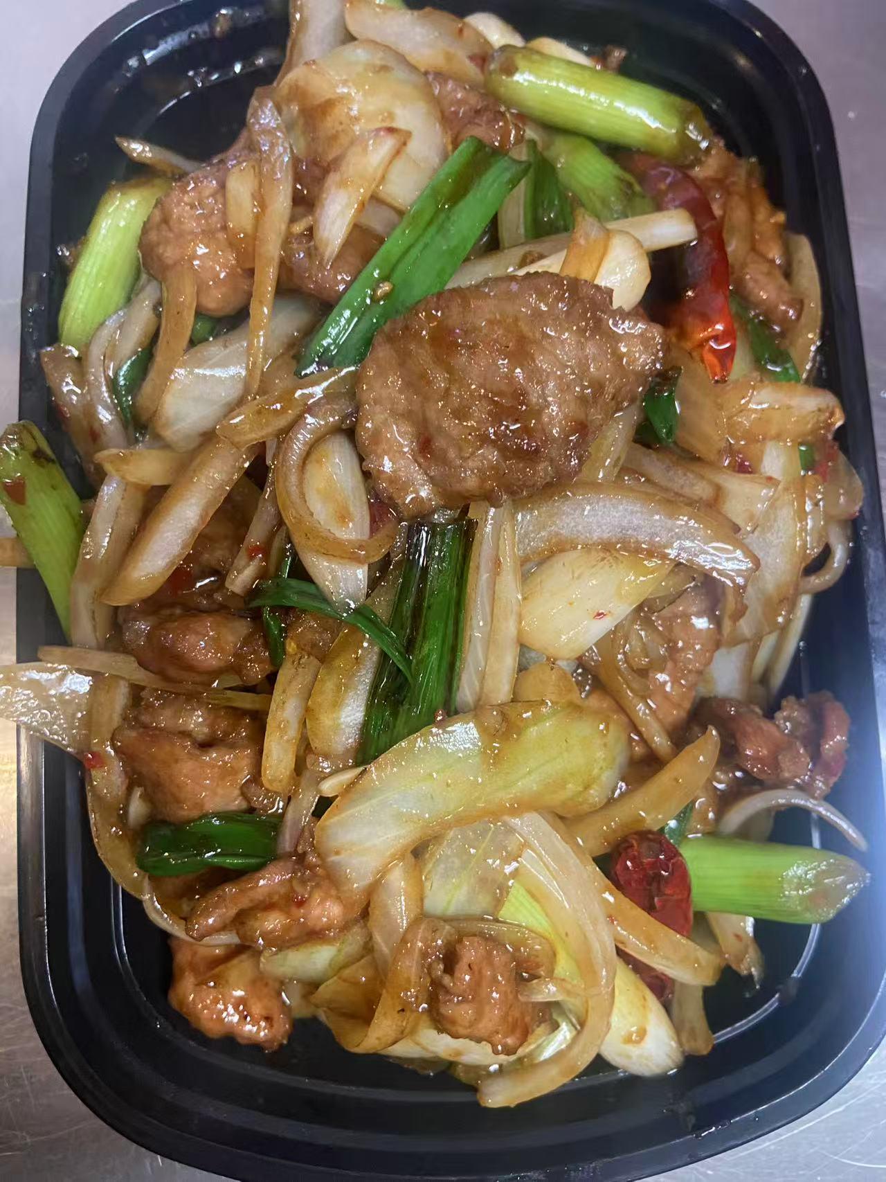 Stir-fried sliced meat with onions and scallions in a black takeout container