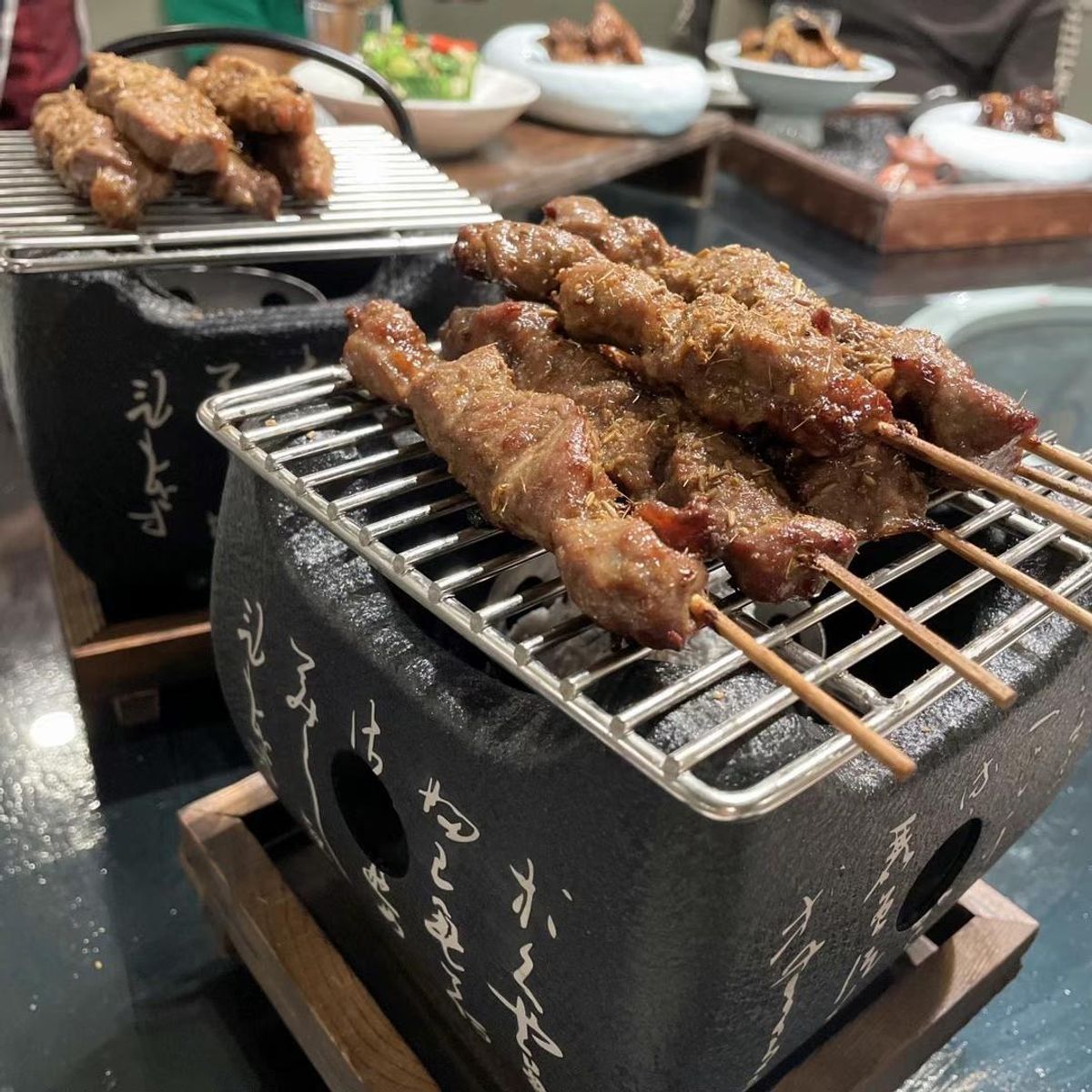 Grilled lamb skewers on a tabletop grill at Chef Huang, a Chinese Restaurant in New York