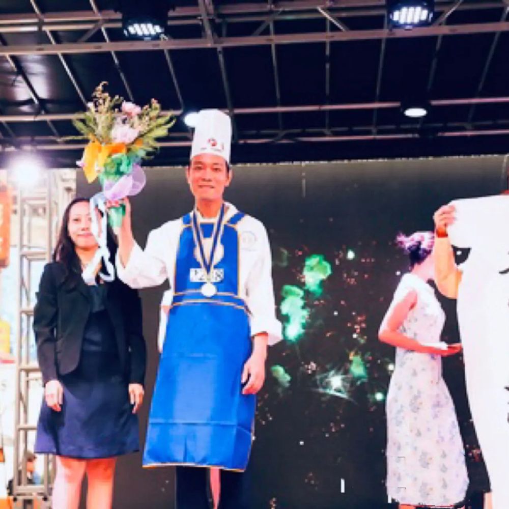 Award-winning chef holding flowers on stage at Chef Huang, a Chinese Restaurant in New York