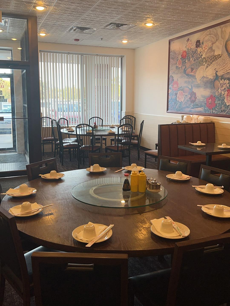 The interior of a Chinese restaurant with round tables, chairs, and decorative wall paintings