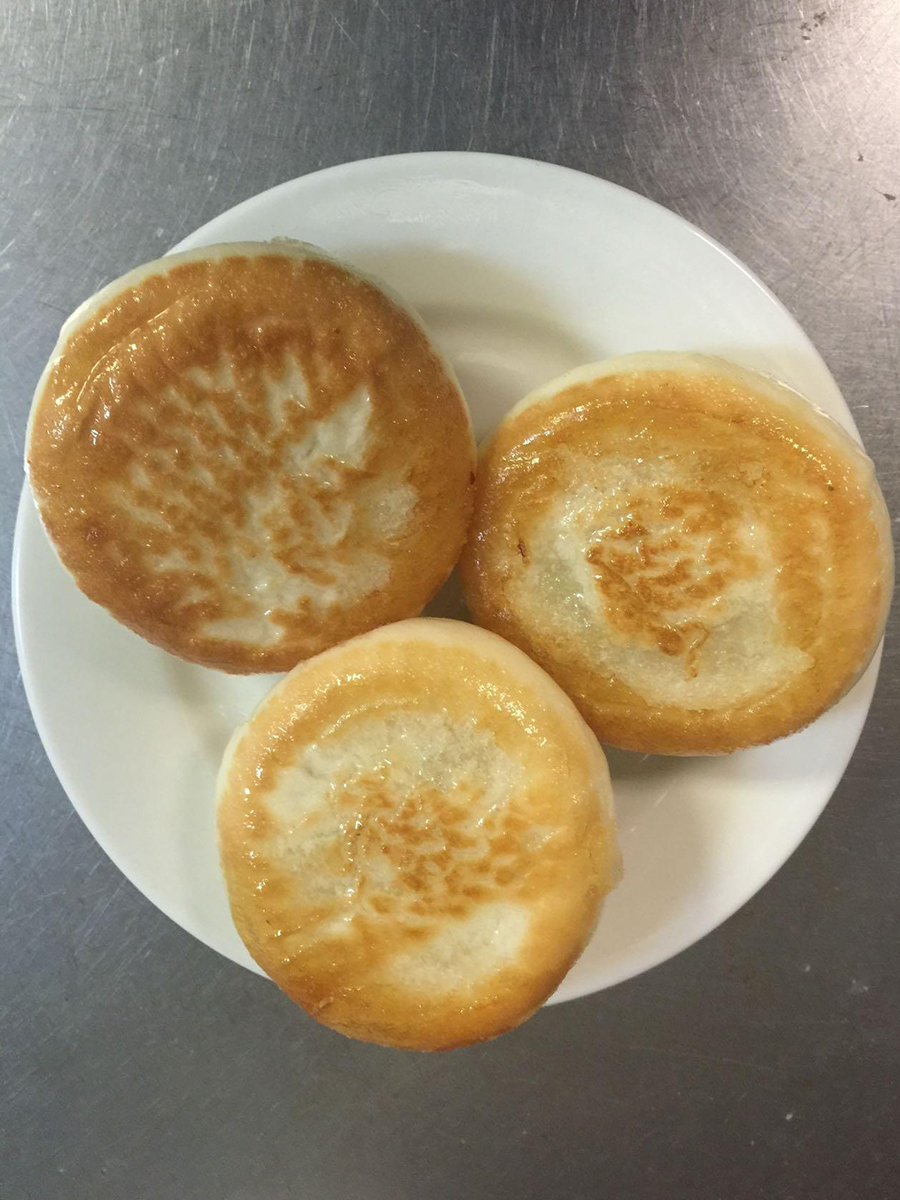 Three golden brown pan - fried buns on a white plate at Cheng's Restaurant，a Chinese Restaurant in Rochester Hills
