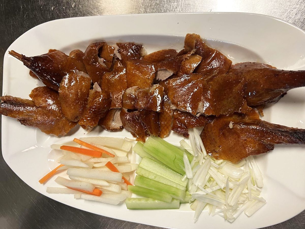 Cheng's-Restaurant-Chinese-Restaurant-Peking-duck-Rochester-Hills Sliced Peking duck on a white plate, accompanied by julienned cucumbers, onions, and radish at Cheng's Restaurant,a Chinese Restaurant in Rochester Hills
