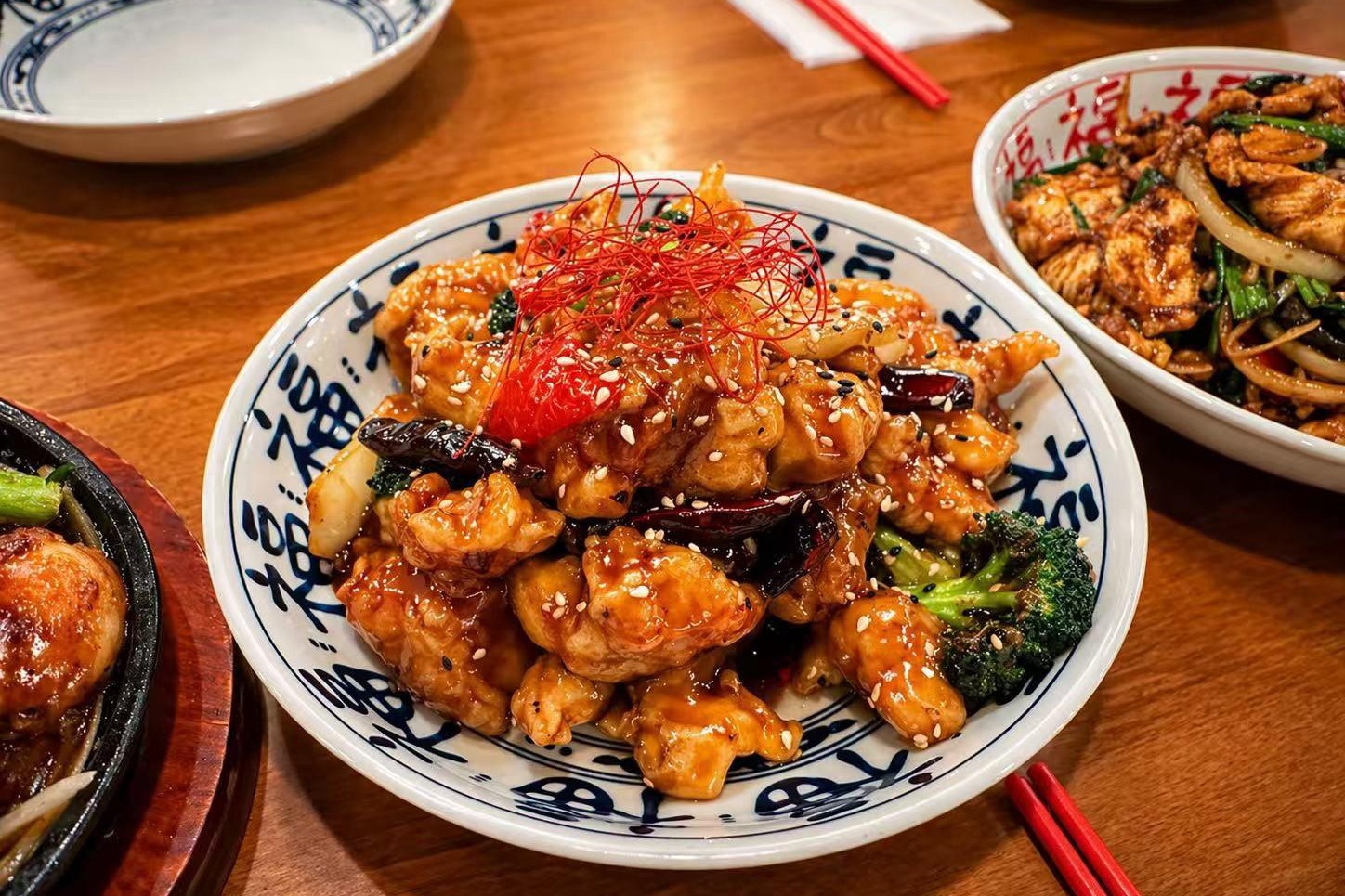 Glazed spicy chicken with sesame, broccoli and chili garnish on fortune‑pattern bowl at Golden Dragon Restaurant a Chinese Restaurant in East Troy