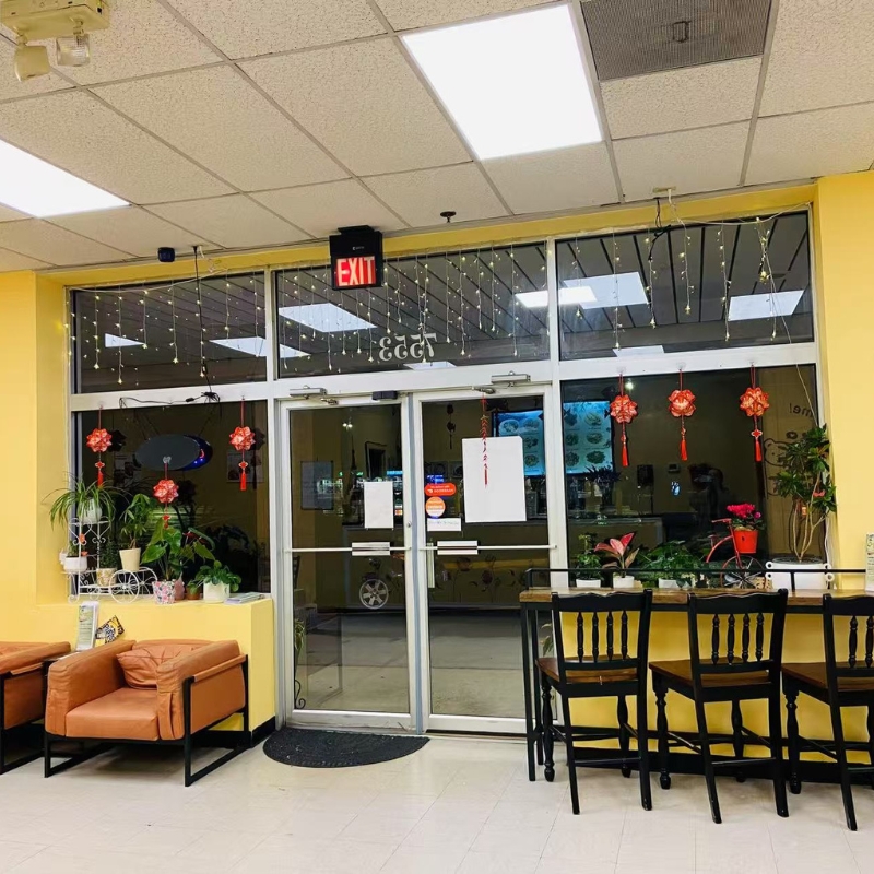 Entrance of Chopsticks Express with yellow walls, plants, and an exit sign.