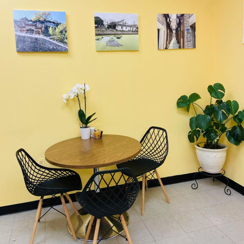 Round table area in Chopsticks Express, yellow walls, plants, and black chairs.