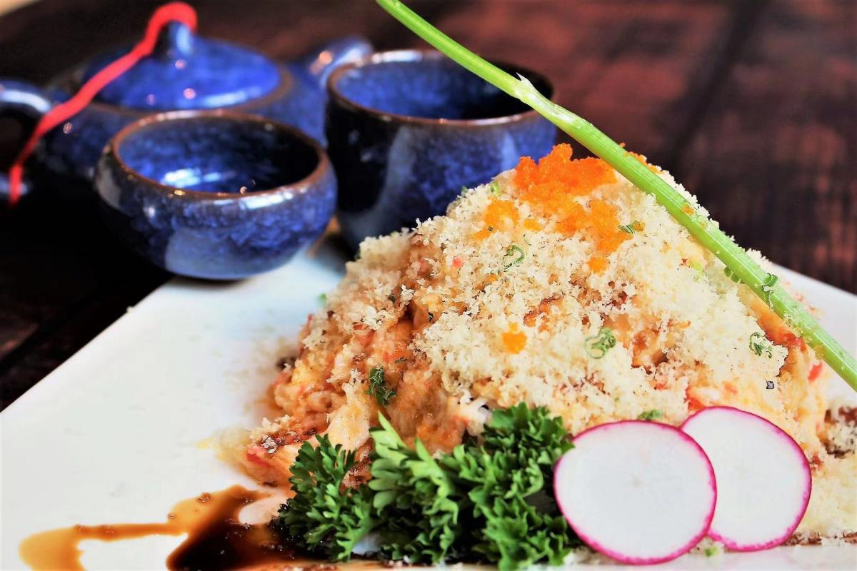 Crispy fried sushi mound topped with fish roe, garnished with parsley and radish beside blue ceramic teaware at Chopsticks China Bistro & Sushi Bar, a Asian fusion restaurant in Cumming