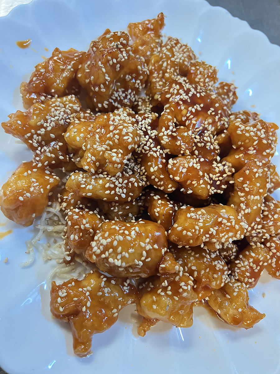 Chopsticks-Asian-Bistro-Asian-Restaurant-Sesame-chicken-Littleton Golden sesame chicken pieces coated in glossy sauce, sprinkled with white sesame seeds, served on a white plate at Chopsticks Asian Bistro,a Asian Restaurant in Littleton