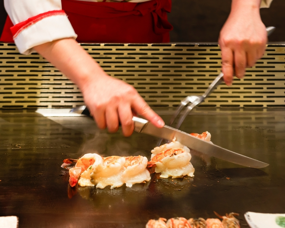 Chef slicing grilled shrimp on hibachi grill at Chow's Ramen & Hibachi, a Authentic Japanese Restaurant Chandler
