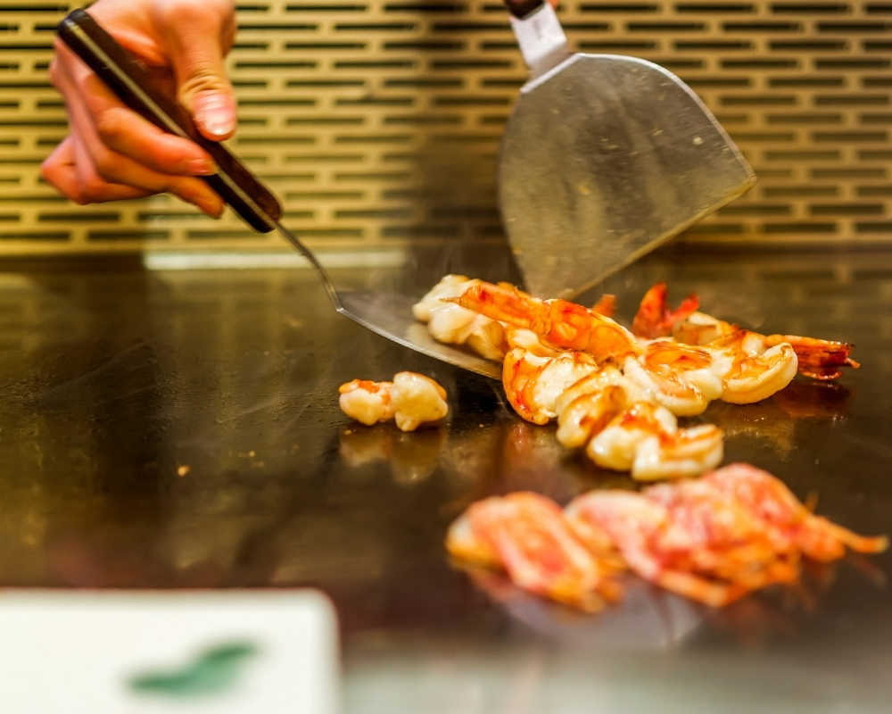 Chef tossing fresh shrimp on hot hibachi grill at Chow's Ramen & Hibachi, a Authentic Japanese Restaurant Chandler
