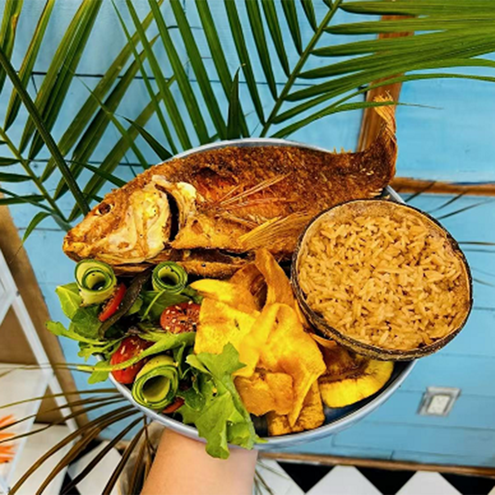 Platter of crispy whole fried fish, coconut rice, plantain chips, and salad at Costa，a Colombian Restaurant in Houston