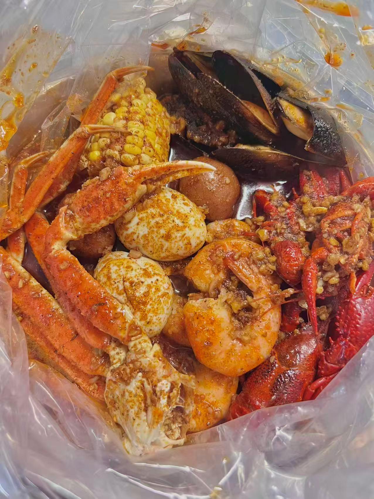 Seafood boil in a plastic bag with crab legs, shrimp, corn, sausage, and eggs