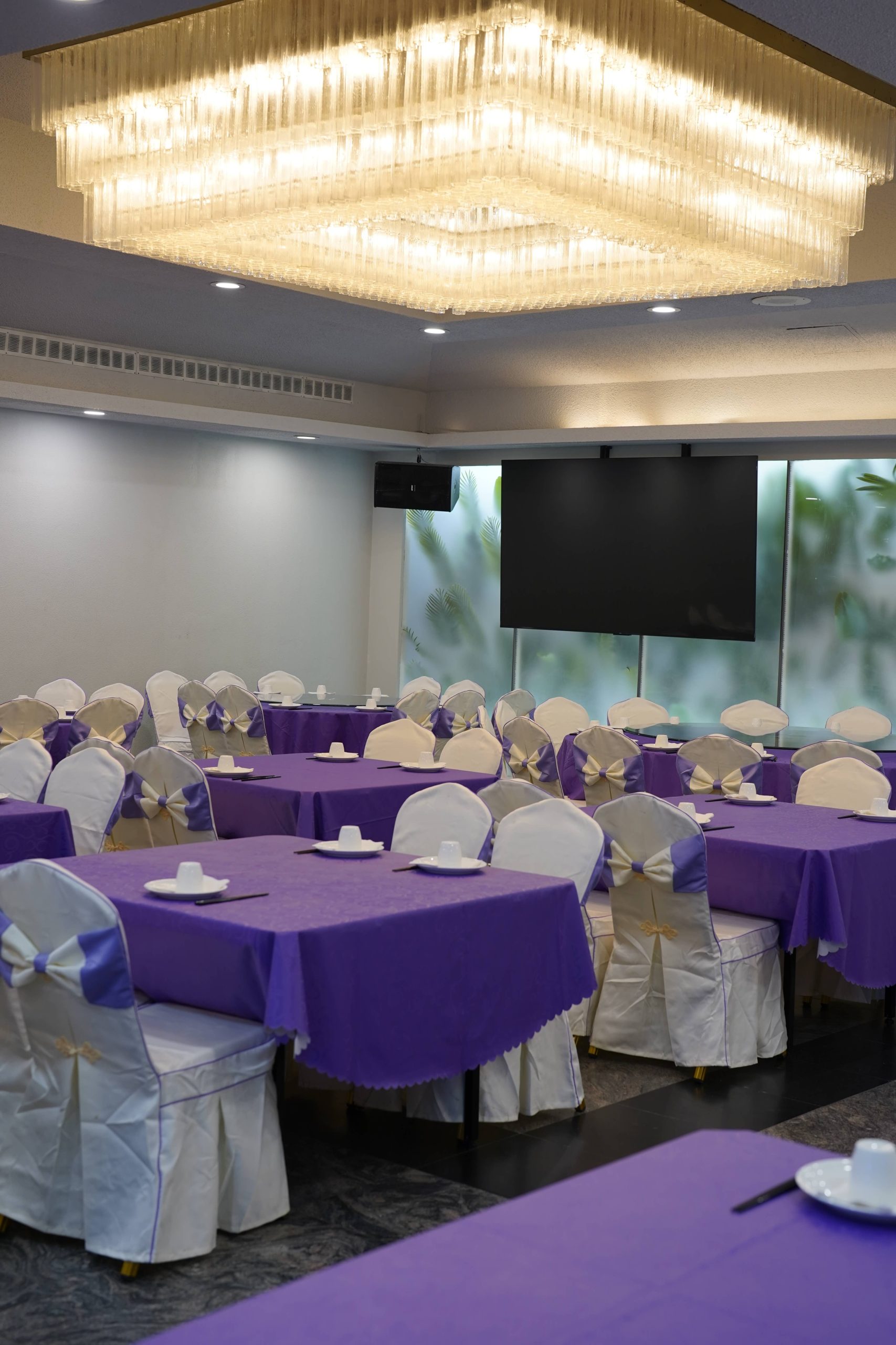 Banquet hall with purple tablecloths and crystal chandelier at Dak Sing Palace, a Chinese Restaurant in Brooklyn