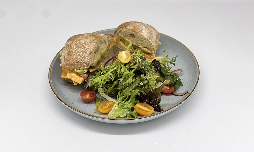 a plate of sandwich with fresh salad at Dandelion Kaffe，a Brunch Restaurant in Alameda