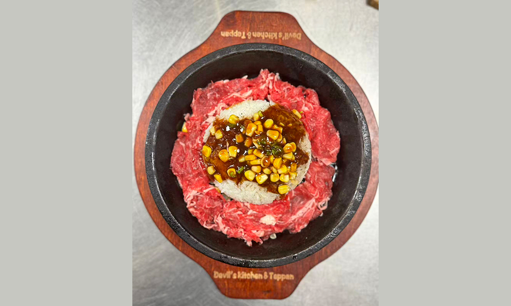 Tender beef slices with rice and corn in a hot stone bowl, a savory teppan dish at Devils Kitchen & Teppan, a Asian Restaurant in Eastvale