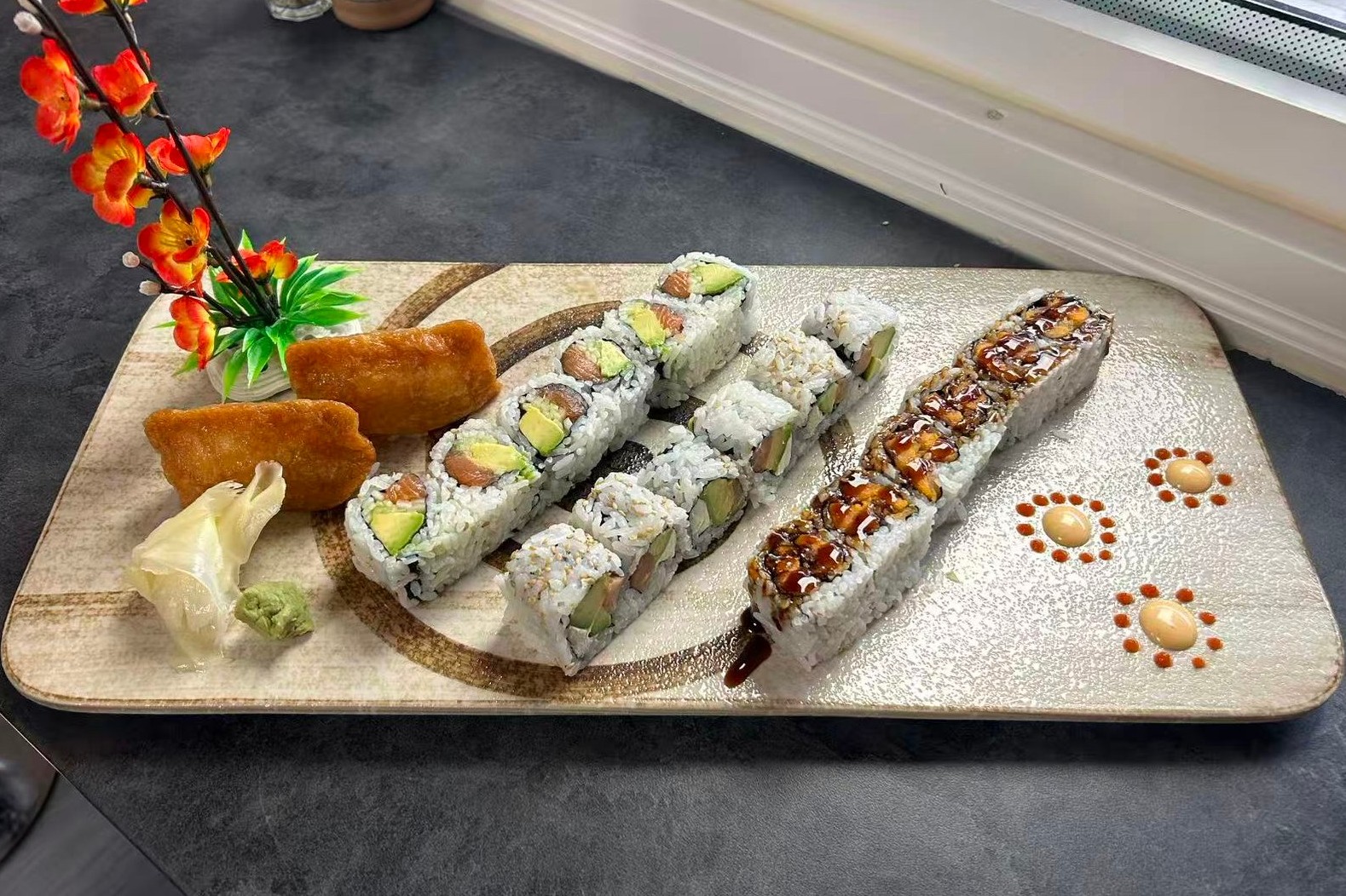 Dharma-Sushi&Grill-Japanese-Restaurant-Mixed-Sushi-Rolls-Platter-Schenectady Platter with a variety of sushi rolls, garnished with flowers at Dharma Sushi & Grill, a Japanese Restaurant in Schenectady