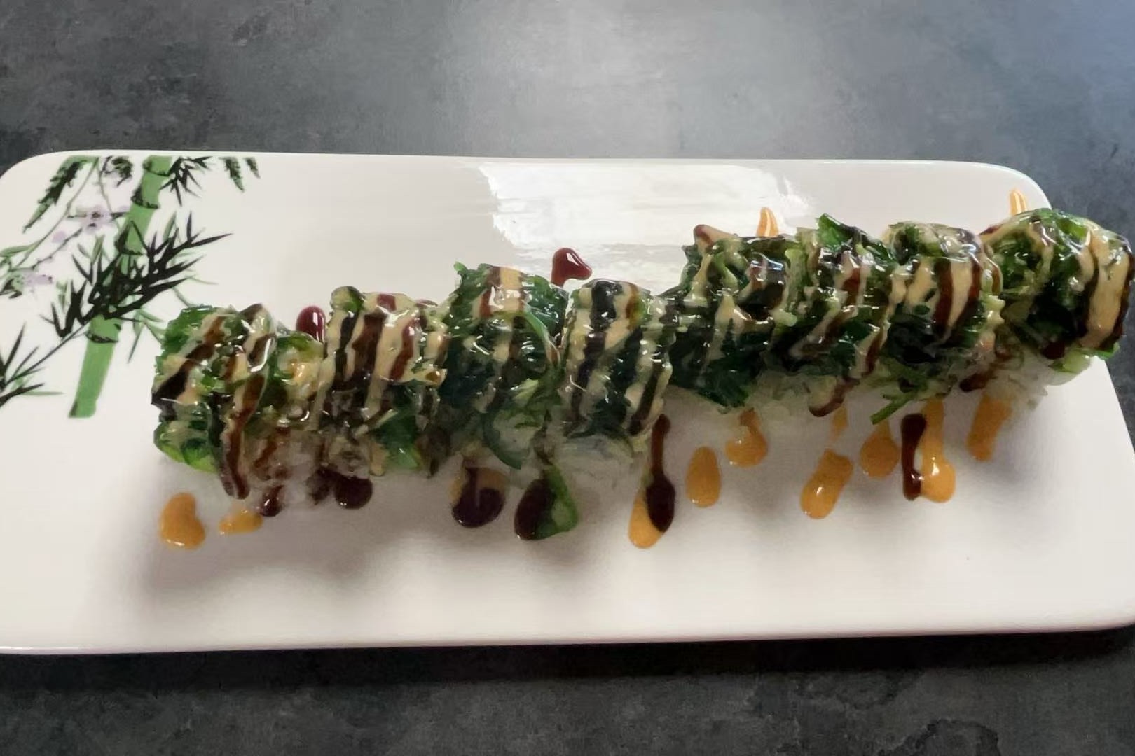 Dharma-Sushi&Grill-Japanese-Restaurant-Seaweed-Sushi-Roll-Schenectady Sushi roll topped with seaweed and drizzled with sauces at Dharma Sushi & Grill, a Japanese Restaurant in Schenectady
