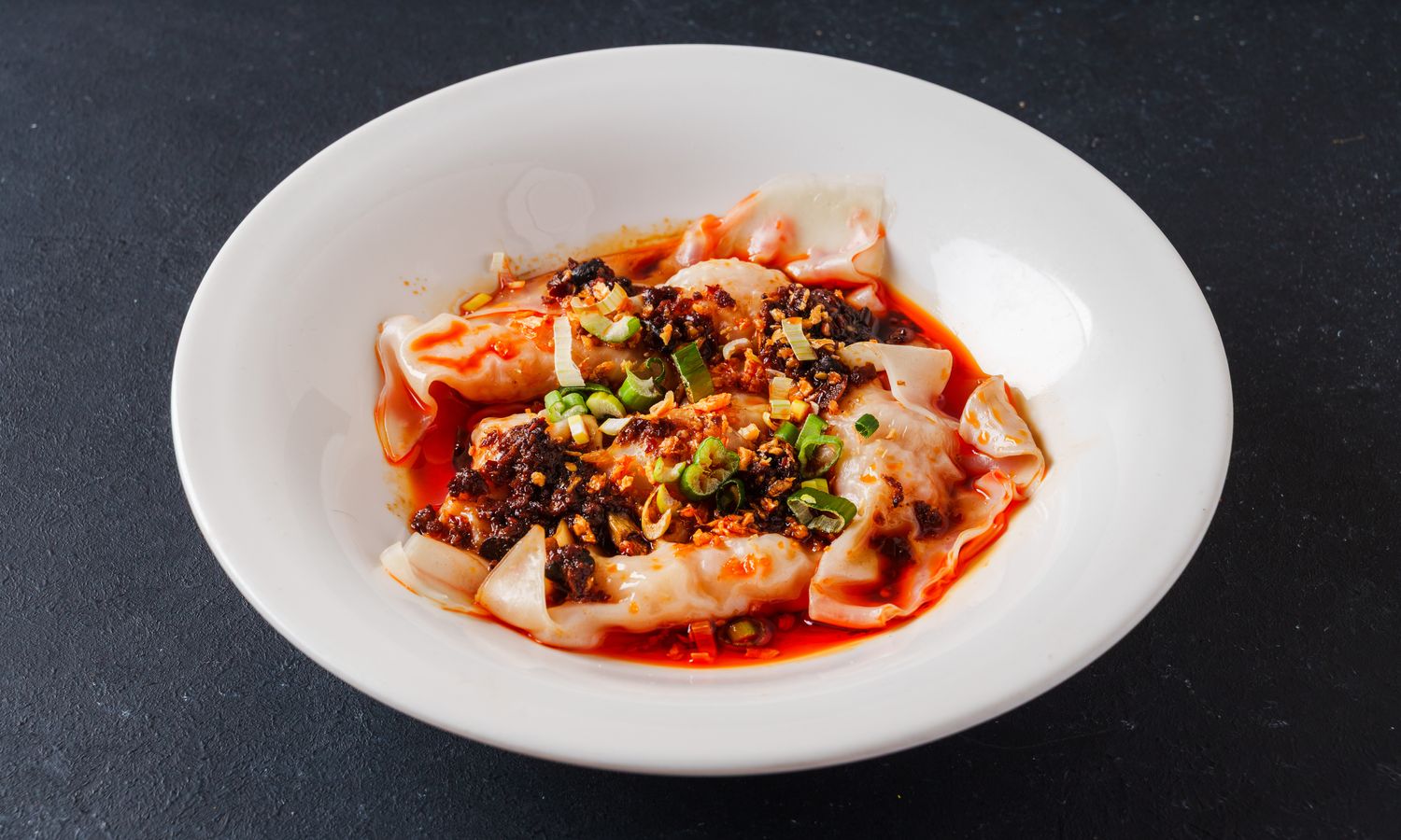 Pork wontons in spicy red oil with chili and scallions at Dim Sum Bloom Rockville Centre, a Chinese Restaurant in Rockville Centre