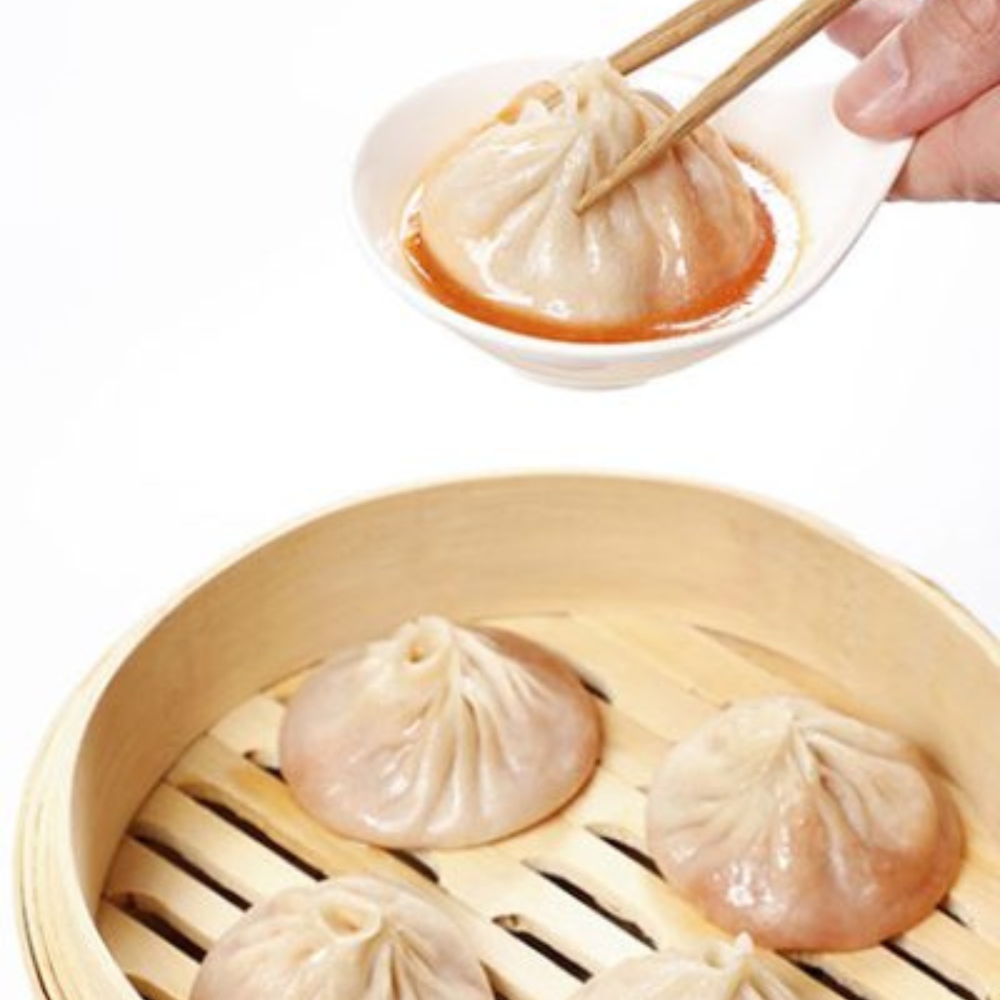 Soup dumpling dipped in savory sauce at Tom's Dim Sum, a Dim Sum Restaurant in PA