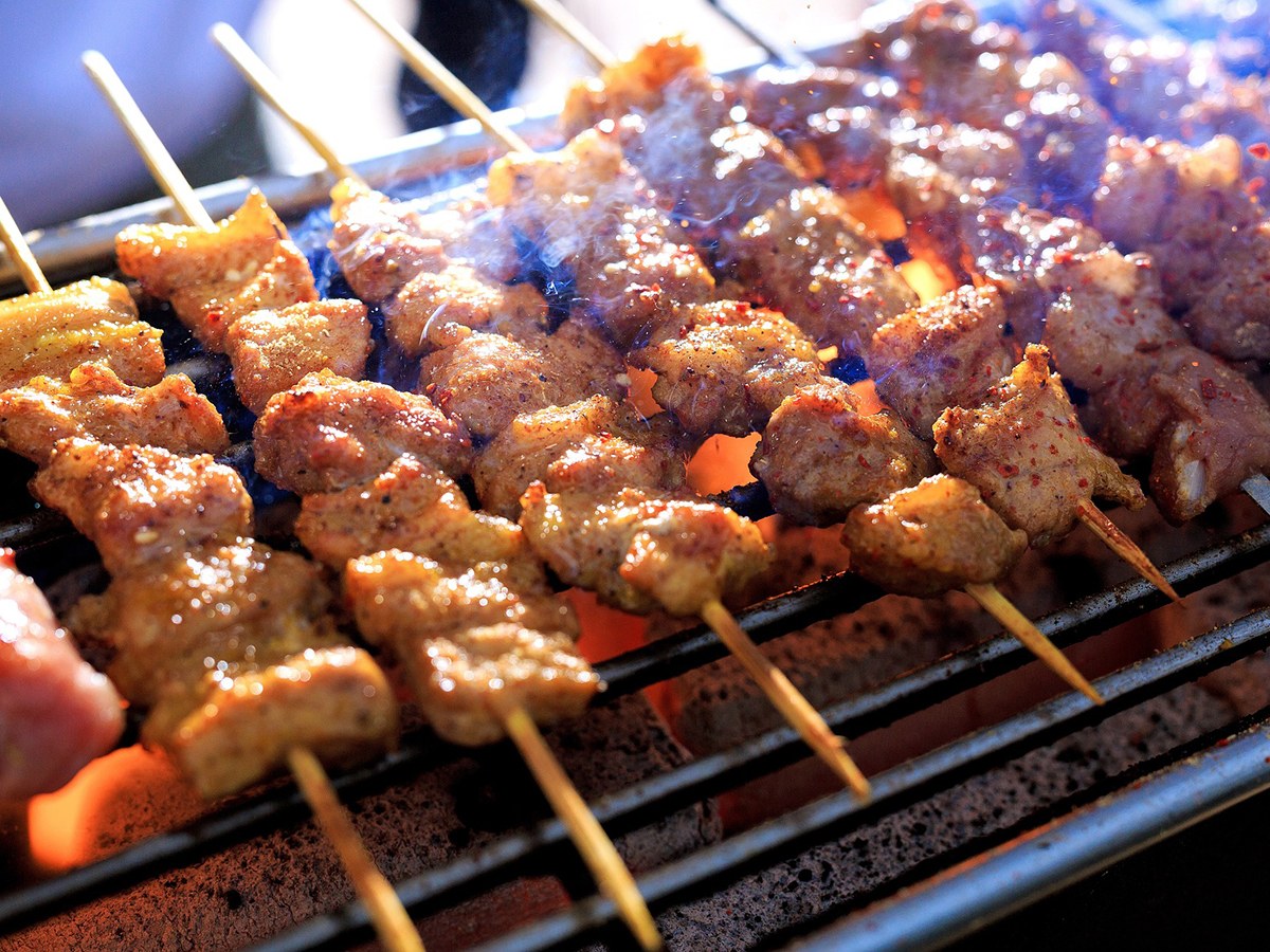 Spicy grilled meat skewers smoking over charcoal at Ditan Er BBQ, a Barbecue restaurant in Flushing