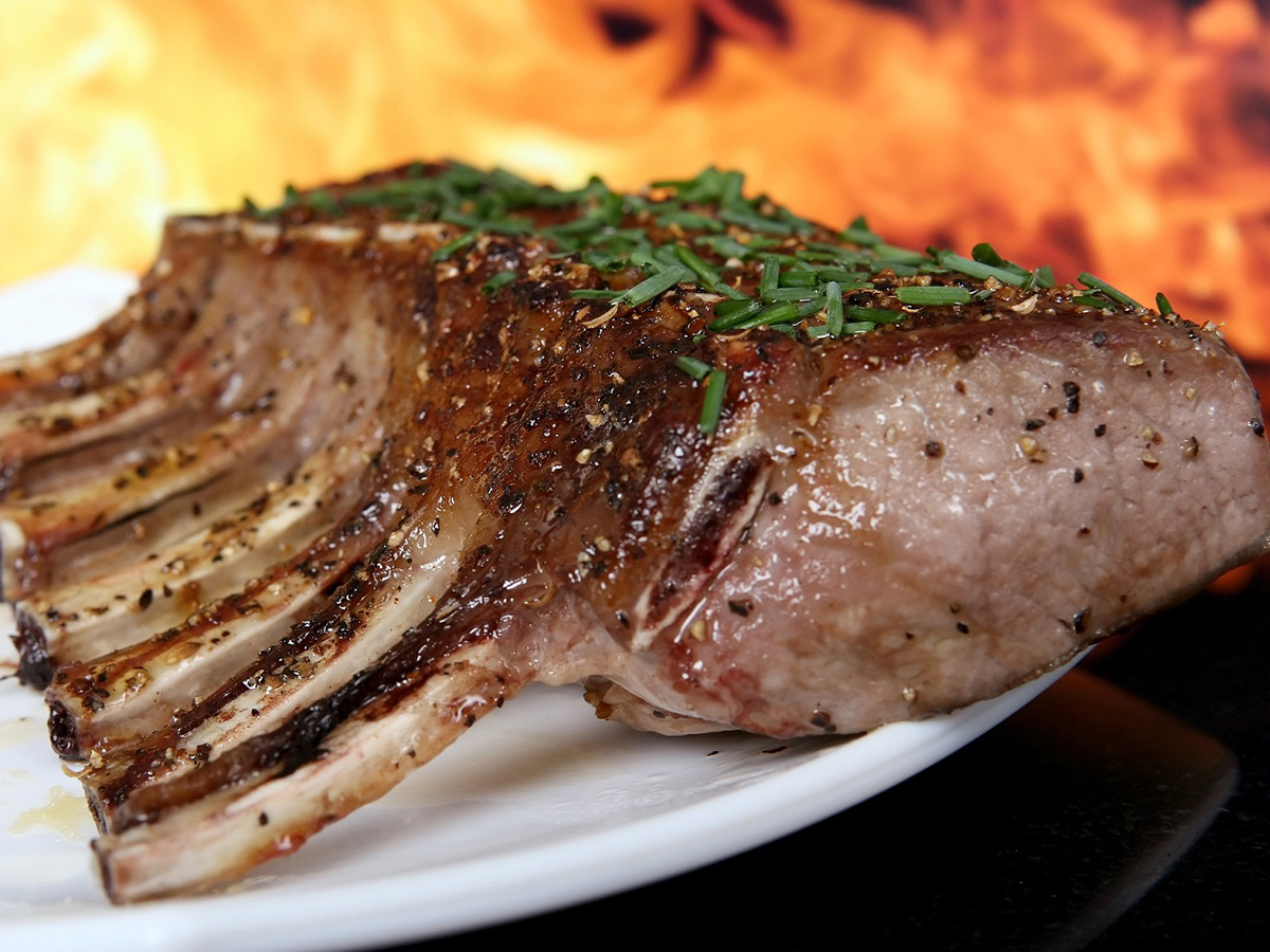 Herb-seasoned grilled rack of lamb with a flame backdrop at Ditan Er BBQ, a Barbecue restaurant in Flushing