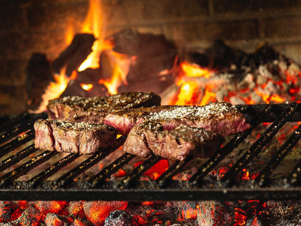 Grilled steaks cooking over open fire with salt seasoning at Ditan Er BBQ, a Barbecue restaurant in Flushing