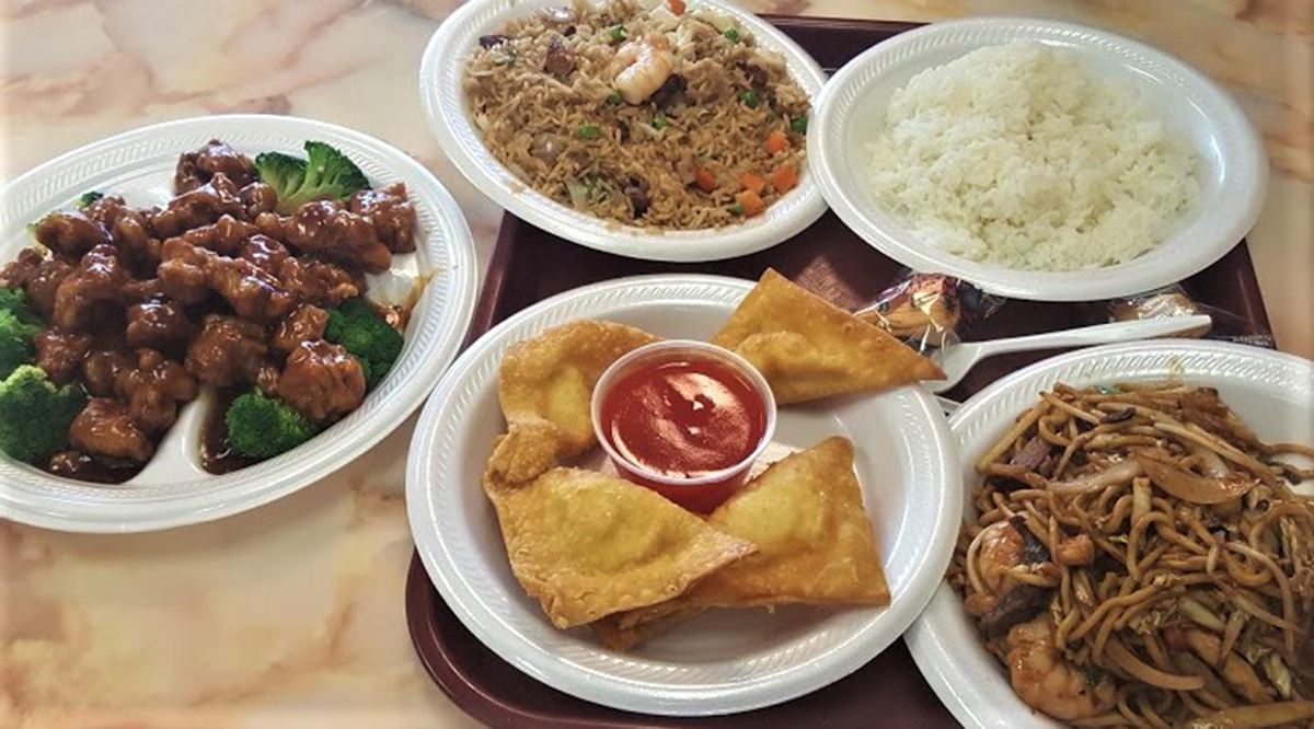 Plastic plates with assorted Chinese takeout: General Tso's chicken, shrimp fried rice, lo mein, crab rangoon with sweet and sour sauce and white rice.