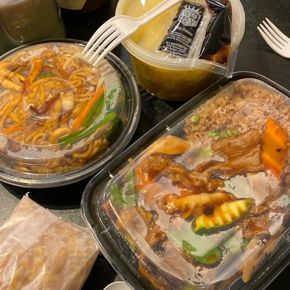 Multiple sealed plastic takeout containers with lo mein, beef stir fry, fried rice, soup and crab rangoon, ready-to-eat Chinese takeout.