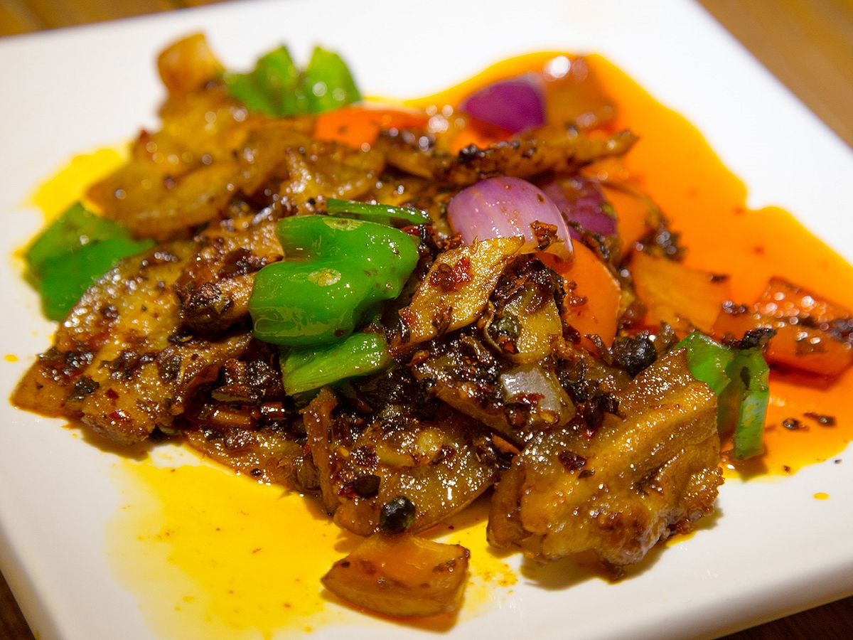 Spicy stir-fried eggplant with bell peppers and onions on a square white plate at Dragon Inn, a Chinese Restaurant in Fredericksburg