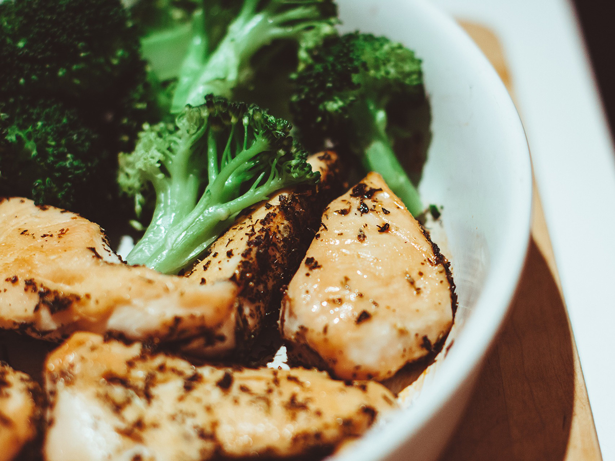 Seasoned grilled chicken pieces paired with fresh broccoli inside a white bowl at Dragon Inn, a Chinese Restaurant in Fredericksburg