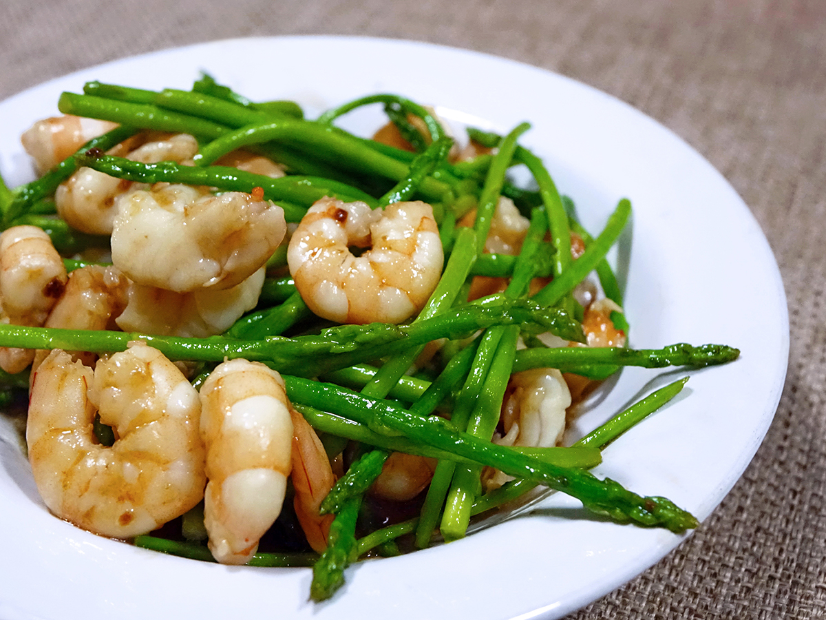 Stir-fried shrimp and fresh green asparagus arranged on a white ceramic plate at Dragon Inn, a Chinese Restaurant in Fredericksburg