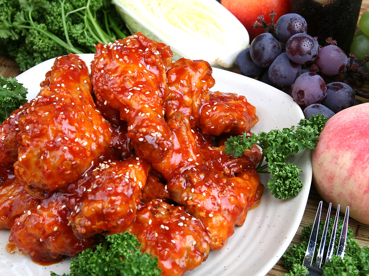 Spicy glazed chicken wings topped with sesame seeds garnished with fresh greens on a plate at Dragon Inn, a Chinese Restaurant in Fredericksburg