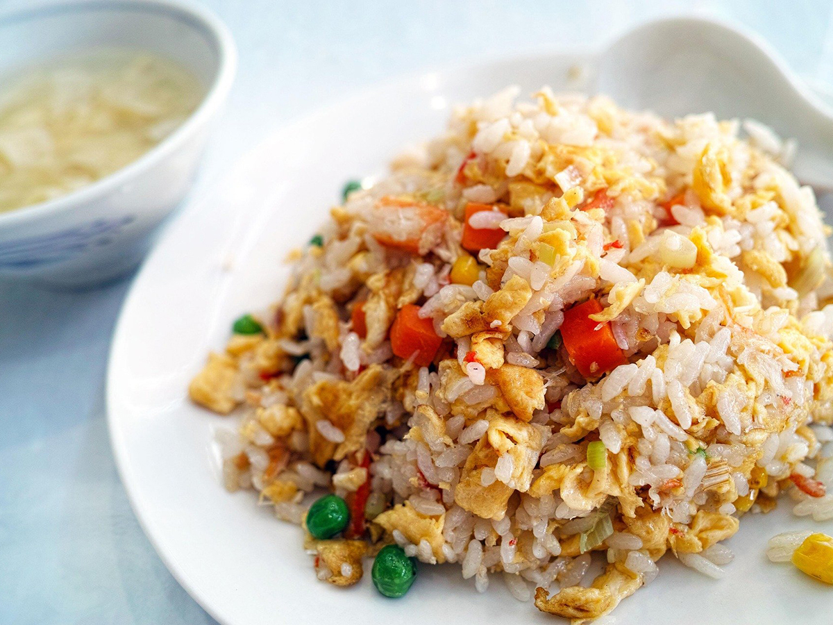 House vegetable and egg fried rice paired with light soup on white plate at Dragon Inn, a Chinese Restaurant in Fredericksburg