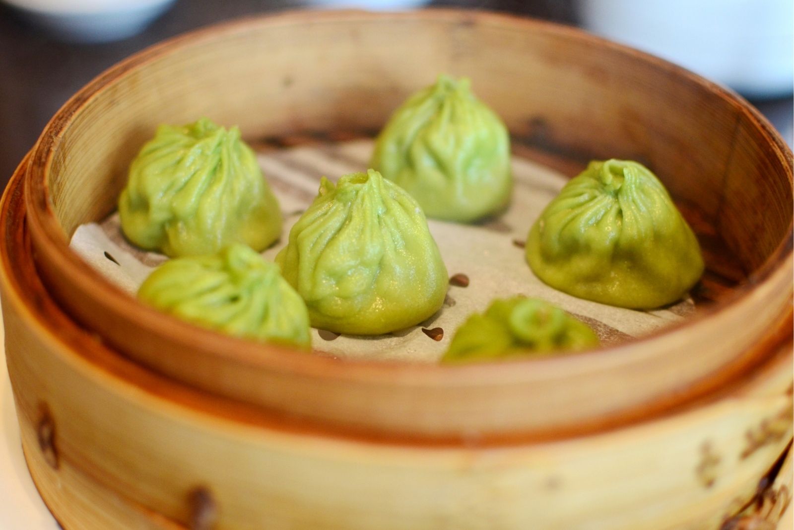 Steamed soup dumplings with spinach dough and savory broth at Dumpling Bay, a Chinese Restaurant in Golden