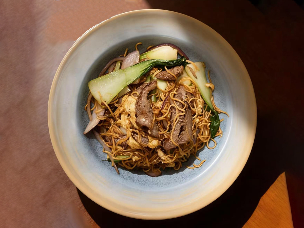 A bowl of savory beef chow mein with fresh vegetables at Dumpling House, an Asian Restaurant in Harrisonburg