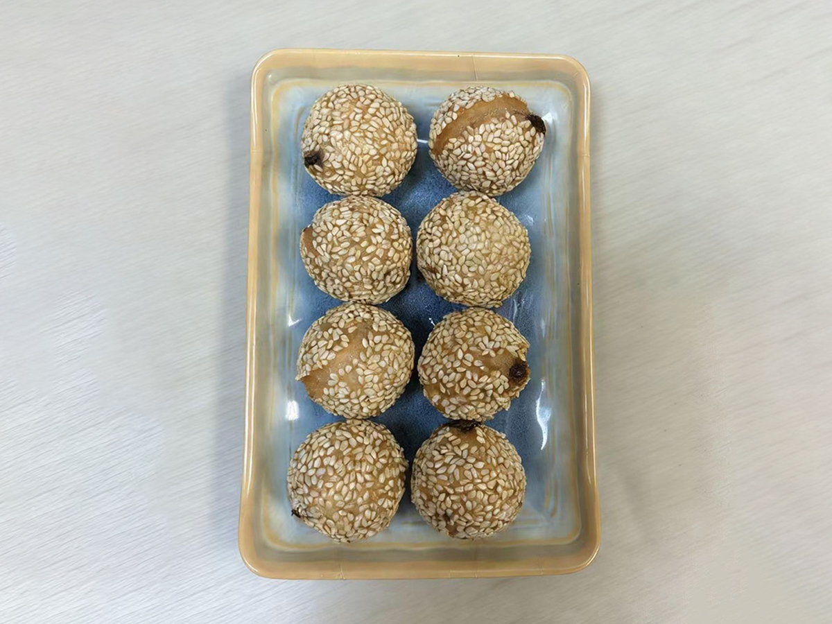 Eight glutinous sesame balls on a blue plate at Dumpling House, an Asian Restaurant in Harrisonburg