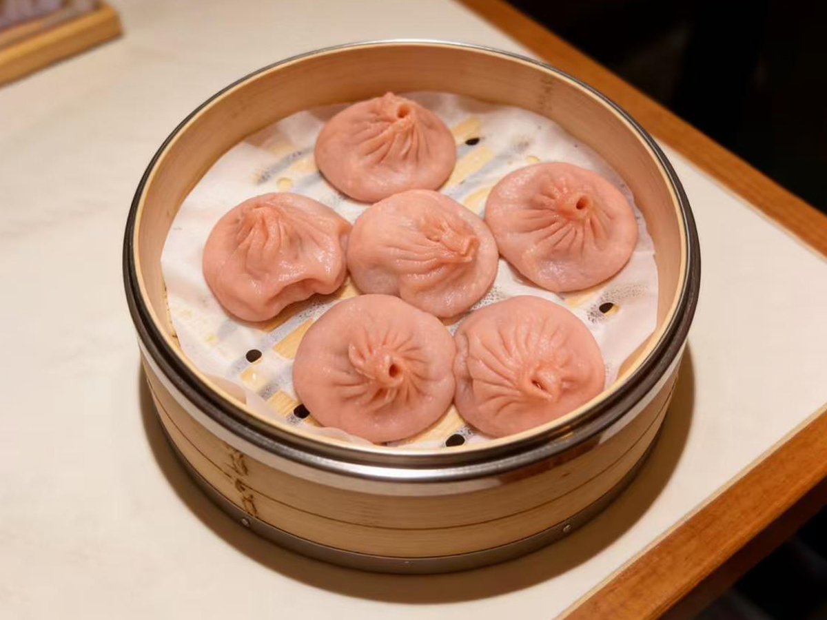 Six pink soup dumplings in a bamboo steamer at Dumpling House, an Asian Restaurant in Harrisonburg