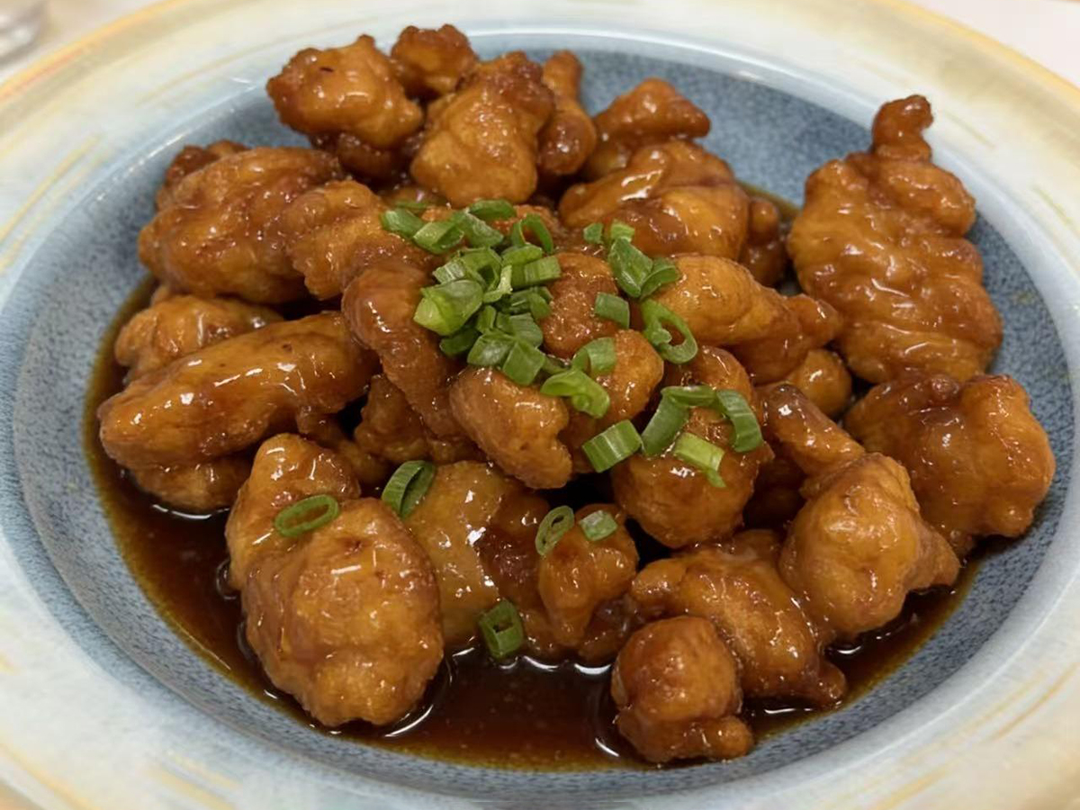 Sweet and sour pork coated in glossy sauce, garnished with green onions at Dumpling House, an Asian Restaurant in Harrisonburg