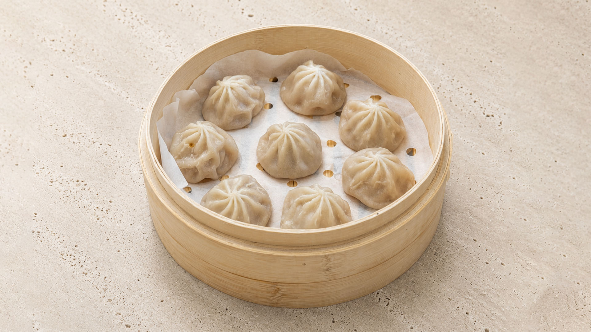 Eight soup dumplings (Xiao Long Bao) in a bamboo steamer