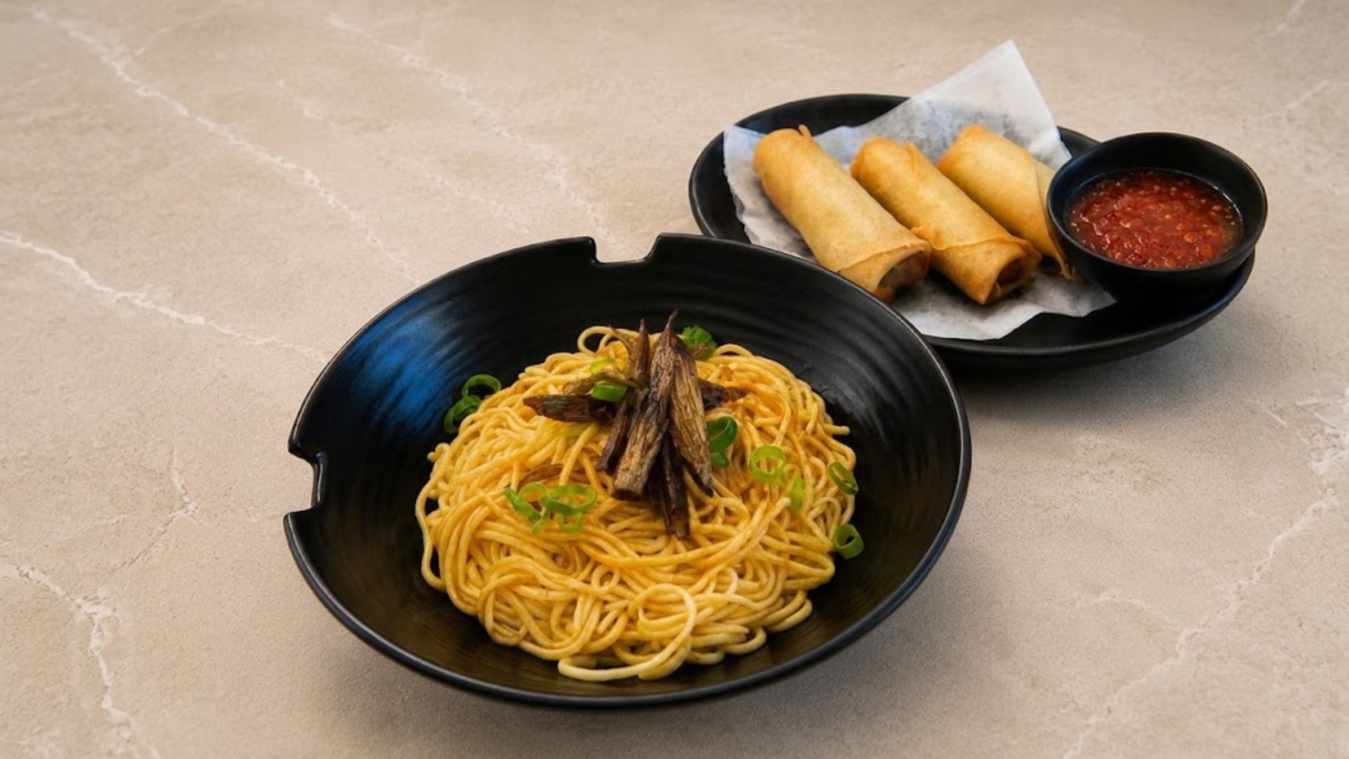 Noodles with mushrooms and scallions, alongside spring rolls and sweet chili sauce