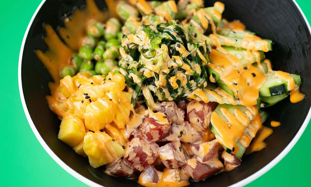 Colorful poke bowl with raw tuna, mango, cucumber, seaweed and creamy spicy dressing in black ceramic bowl at Dumplings & Tea, a Asian Restaurant in Chesterfield