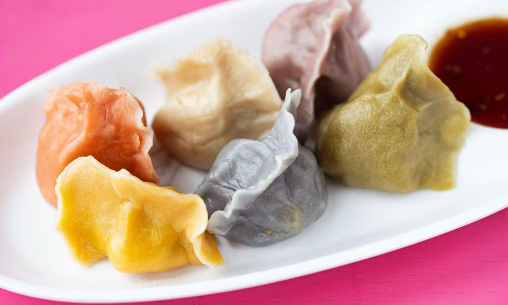 Assorted colorful steamed dumplings served on white oval plate alongside dark soy dipping sauce at Dumplings & Tea, a Asian Restaurant in Chesterfield