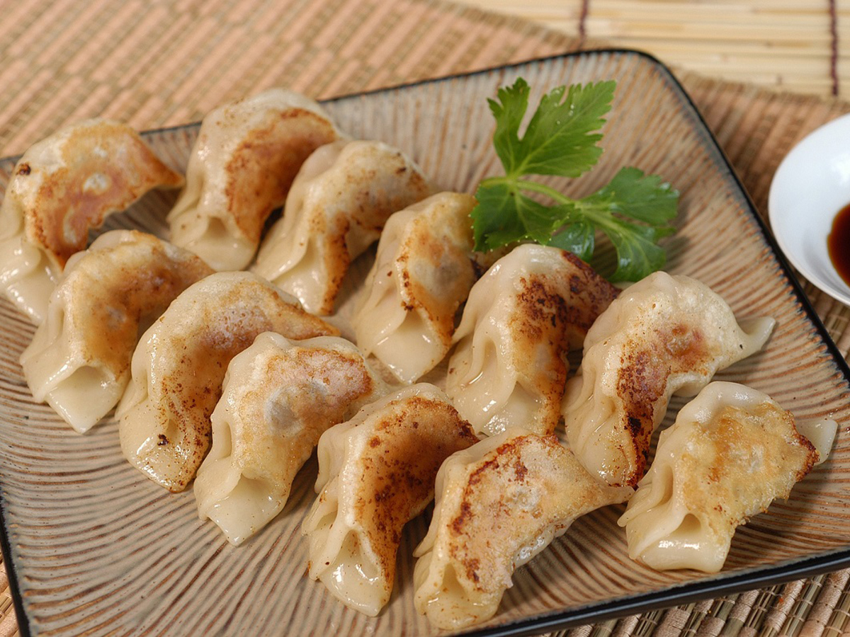 Pan - fried dumplings with meat filling, golden - brown from cooking at Dumpling Zone, a Chinese restaurant in San Francisco